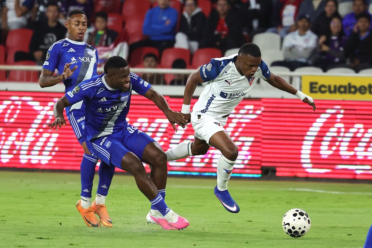 Yerlin Quiñónez, de Liga de Quito, se saca la marca de dos jugadores de Emelec. Foto: API